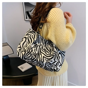 Detailed close-up of zebra pattern knit tote bag with black strap and gold metal hardware