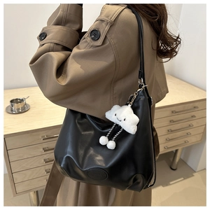 Dettaglio della borsa hobo nera in finta pelle con logo inciso e ciondolo a nuvola