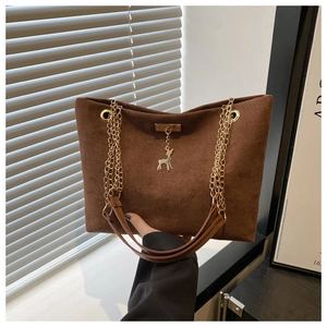 Detailed close-up of large tote bag with golden chain and deer metal pendant charm