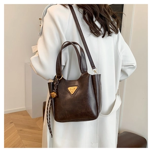 Detail of vintage brown bucket bag with triangular metal logo and woven rope charm