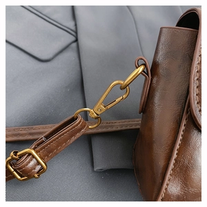 Detail of dark brown vintage leather bag with golden metal hooks and fine stitching