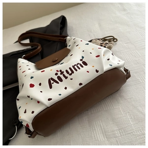 Dettaglio dell'elegante motivo a pois e della tracolla in pelle di questa borsa tote