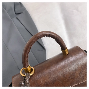 Close-up of retro brown faux leather handbag with metallic hardware and woven rope detail