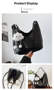 Detail view of black PU leather half-moon tote with plush cloud charm and logo