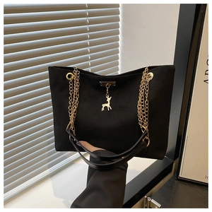 Close-up of black suede tote bag with dual gold chain straps and a gold deer charm detail