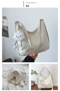 Detail of creamy white tote bag with wide strap and cloud plush pendant