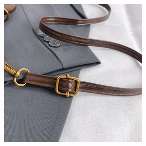 Detailed macro view of vintage bronze metal buckle and dark brown leather shoulder strap