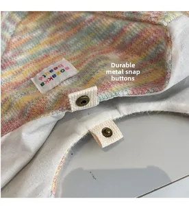Dettaglio della borsa in maglia a righe colorate con un bottone a pressione in metallo bronzo