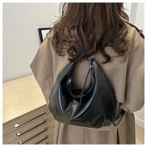 Model wearing a large black matte PU leather hobo bag with a minimalist moon shape