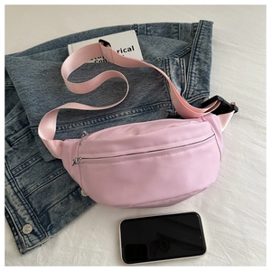 Detailed view of pink nylon crossbody bag with adjustable strap on denim jacket