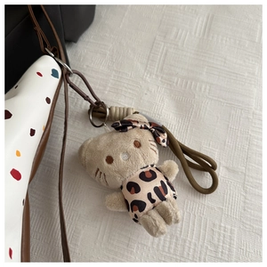 Dettaglio di un ciondolo gatto in peluche con fiocco leopardato su borsa a pois