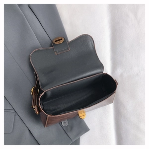 Macro view of vintage brown leather handbag interior with bronze clasp on fabric background