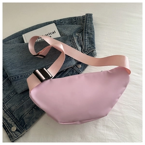Flat lay of pink nylon crescent waist bag on denim jacket with adjustable strap detail