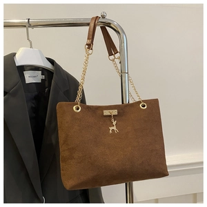 Detail of dark brown matte tote with gold chain strap and reindeer pendant on a blazer