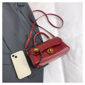 Detail of red vintage crossbody bag with gold twist lock and woven charm accessory