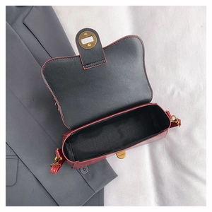 Top view of open red leather crossbody bag showing spacious black interior and gold lock