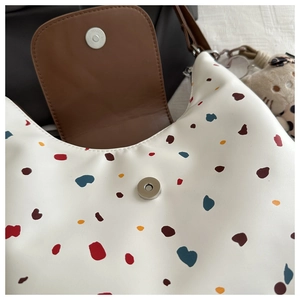 Dettaglio borsa shopper bianca a pois colorati con patta in pelle e ciondolo peluche