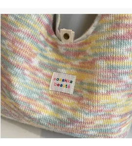 Dettaglio della borsa in maglia a righe arcobaleno con bottone a pressione e etichetta