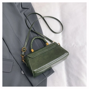 Close-up of vintage dark green leather handbag with gold-tone hardware and top handle