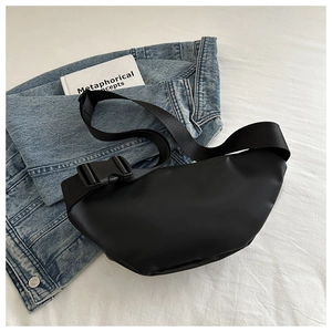 Detail of minimalist black crossbody bag with matte finish on denim and white cloth