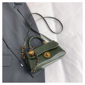 Detailed view of the dark green retro satchel with a golden rotary lock and charm