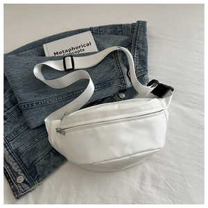 Detail of white PU leather chest bag featuring silver zippers on denim background