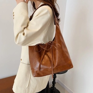 Brown large capacity shoulder tote bag with bow detail worn with corduroy blazer