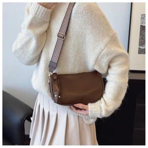 Detail of dark brown half-moon crossbody bag with retro geometric jacquard strap