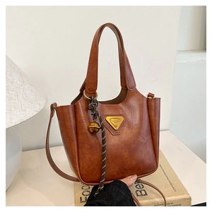Close-up of brown vintage tote bag with gold triangle logo and striped charm detail