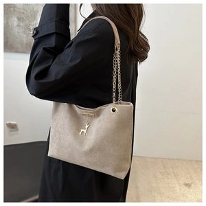 Detailed view of beige suede tote bag with chain strap and elegant deer pendant