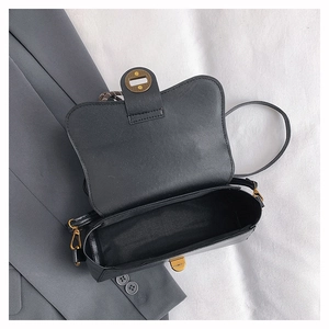 Detail view of the open black minimalist flap handbag with vintage gold metal twist lock