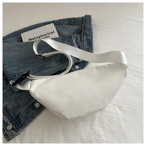 Close-up of white crescent crossbody bag with nylon strap on denim jacket background