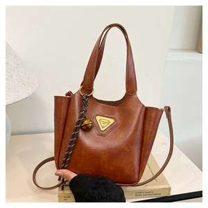 Close-up of caramel vintage leather bucket bag with golden triangle logo and bell charm