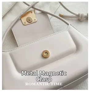 Gros plan du fermoir magnétique doré sur un sac baguette en cuir blanc élégant