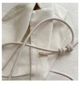 Détail de la bandoulière cylindrique en cuir blanc crème avec nœud et boucle dorée