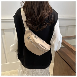 Rear view of a model wearing the minimalist beige nylon crossbody chest bag