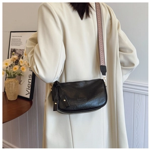 Detail of black faux leather crossbody bag featuring a geometric jacquard wide strap