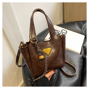 Detail of vintage brown bucket bag showing cracked leather texture and gold hardware