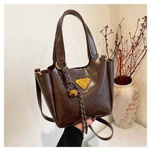 Detail of dark brown oil wax leather bucket bag with triangle logo and gold hardware charms
