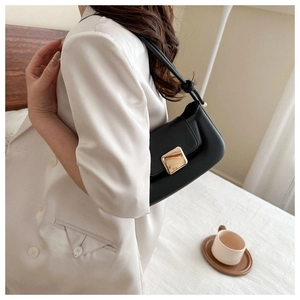 Détail du sac baguette noir avec boucle dorée carrée et bandoulière à nœuds