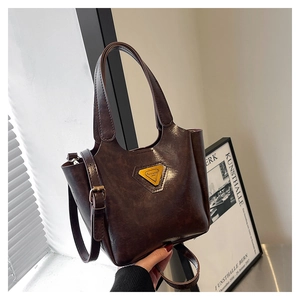 Close-up of retro dark brown leather bucket bag with gold metal plaque and shoulder strap