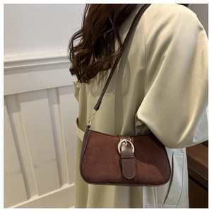 Detail of dark brown suede shoulder bag featuring a vintage gold buckle and smooth leather trim