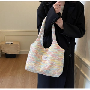 Dettaglio borsa tote in maglia a righe arcobaleno pastello con etichetta logo bianca