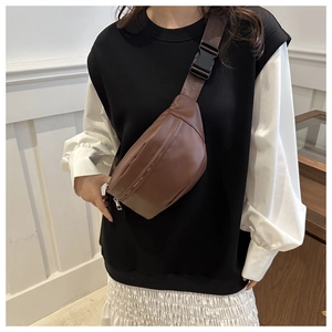 Detail view of a dark brown PU leather crossbody chest bag with silver zipper and strap