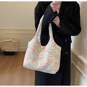 Dettaglio della borsa in maglia a righe arcobaleno con texture morbida ed etichetta