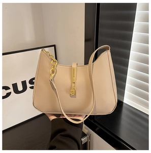 Detail der beige Halbmond-Tasche mit goldener Kette und vertikalem Metallverschluss
