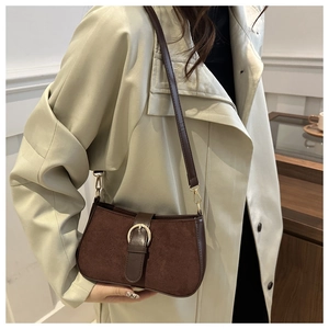 Detailed close-up of dark brown frosted suede handbag featuring a round gold buckle