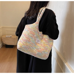 Dettaglio della borsa tote in maglia colorata con etichetta del marchio e tracolla lunga