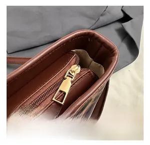 Detail of the golden metal zipper and brown leather piping on the leopard print bucket bag