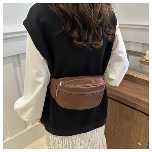 Close-up of brown matte leather waist bag with double silver zippers worn by a model